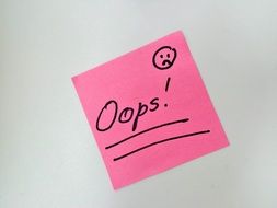 words "oops" on a pink sticky note