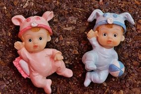 two plastic toy figures of newborn children of a boy and a girl