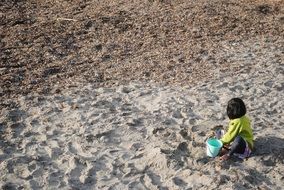 child is playing in the sand on the beach
