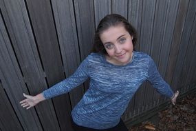 happy caucasian Young Girl posing at grey wooden wall