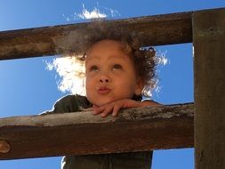 curly child on a wooden fence