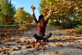 girl on a stone pavement among autumn leaves