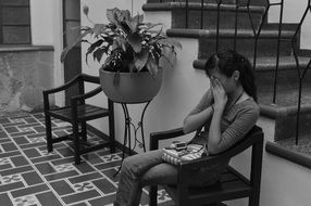 black and white photo of a sad girl on an armchair