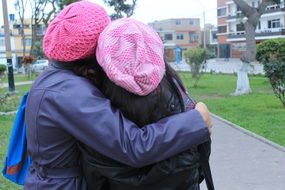 two girls in pink hats embracing outdoor