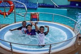happy dark skin man with two child boys in hot tub