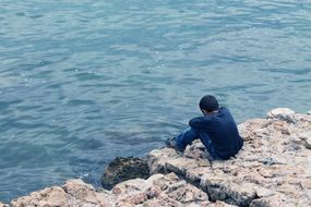 lonely guy sitting on a rock