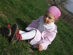 girl in a pink bandana on a green lawn