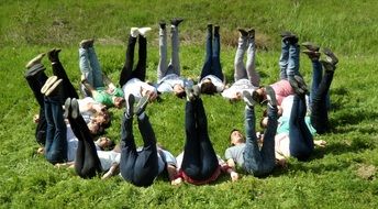 people in a circle with their legs raised on the grass