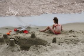 girl is building sand castles on the beach