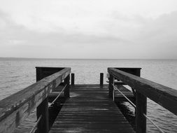 black and white photo of a wooden pier in the ocean