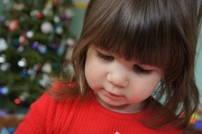 little girl in a red sweater near the Christmas tree