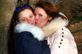 mother kissing adult daughter outdoor