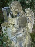 stone statue of a sad angel in a cemetery