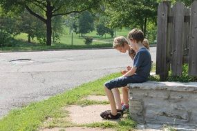 children sit by the fence in the park