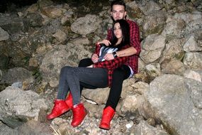 young Couple in Love sitting on Rock at dusk