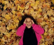 little girl lies on yellow leaves