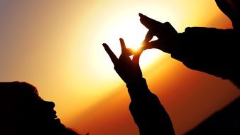 silhouettes of hands at sunset