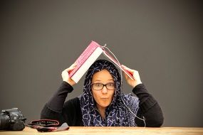 portrait of surprised girl with a book on her head