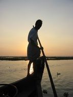man on a boat at dusk, india
