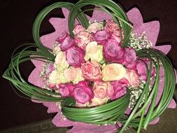 bouquet of roses of different colors in pink paper