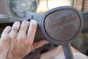 hand lies on the steering wheel of an antique car