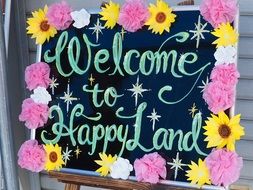 Welcome to happy land, Billboard decorated with flowers