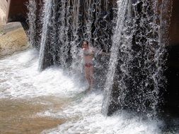 girl stands under a waterfall
