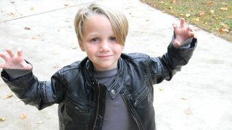 little boy in a leather jacket on the street