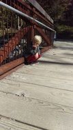 young boy sitting on the wooden bridge