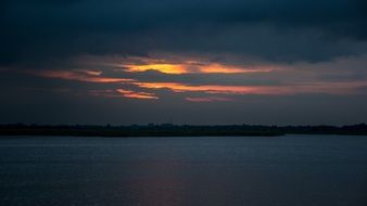 Sunset colors in sky at darkness above water