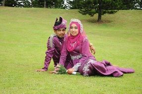 newlyweds on green grass in traditional dress