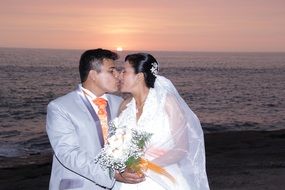 newlyweds kissing at sunset