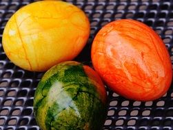 three colorful easter eggs on a trellis
