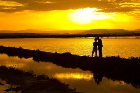 young couple on the shore of the pond at sunset
