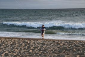 young Girl with kite rope walking at surf line