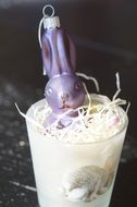 easter decoration in the straw in a glass on a dark background