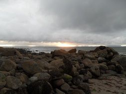 Rocks on the beach and sun on the horizon