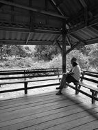 black and white photo of a man at a bus stop