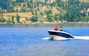 two people on a motorboat on a lake in summer