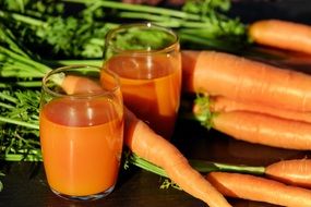two glasses with Carrot Juice and fresh Carrots
