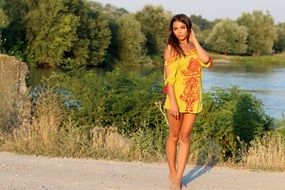 girl in a yellow dress stands on the road