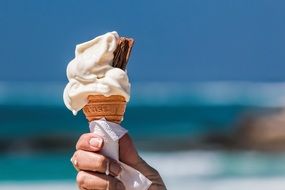 ice cream in a waffle cone in hand close-up on blurred background