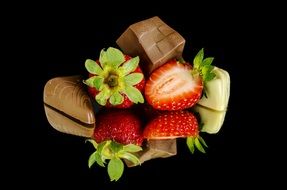 Photo chocolates and strawberries on dark background