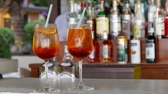 bar with different types of alcohol and in front of him on the table are two cocktails