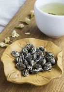 Jasmine Tea, dry leaves and drink in white cup on board