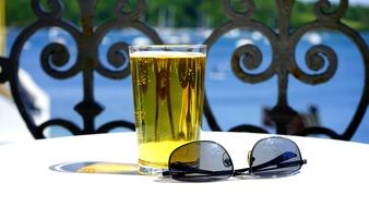 Sunglasses on the table next to a glass of beer