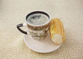 eclair with cream and cup of coffee