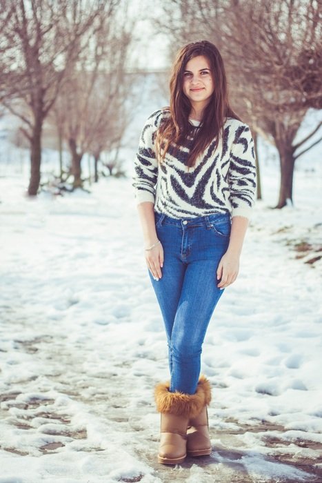 girl in a striped sweater against the background of the winter garden