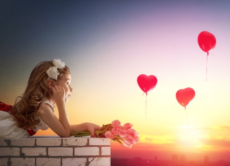 girl lies on a brick wall and looks at balloons