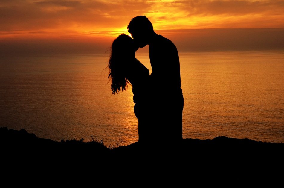 kiss of a couple in love on the background of the sunset